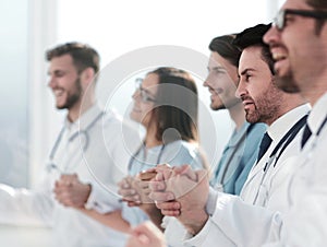 Doctors sit in a row and hold hands of each other