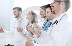 Doctors sit in a row and hold hands of each other