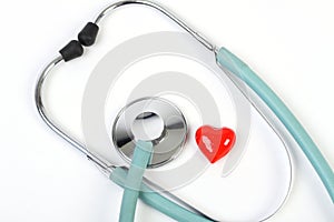 Doctors stethoscope and one small red heart on white background