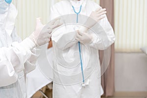 Doctors Surgeon in scrubs putting on surgical gloves. Doctors put on protective glove and mask and suit before proceed patient photo