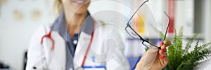 Doctors with tablet and glasses in hands are sitting at table at meeting in clinic closeup