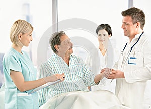 Doctors talking to old patient in hospital