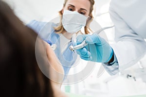 Doctors using dental drill during procedure in modern