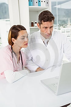 Doctors using laptop together at medical office