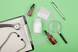 doctors workplace - medical tablet, stethoscope, pills and magnifying glass