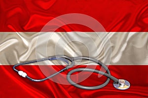 Doctorâ€™s tool, medical stethoscope, lies on the silk national flag of the state of Austria, concept of tourism, insurance,