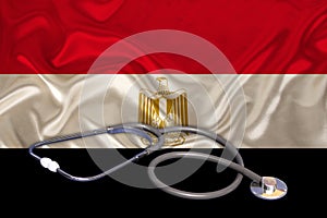 Doctorâ€™s tool, medical stethoscope, lies on the silk national flag of the state of Egypt, the concept of tourism, insurance,