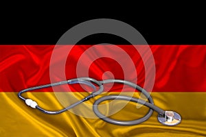 Doctorâ€™s tool, medical stethoscope, lies on the silk national flag of the state of Germany, the concept of tourism, insurance,