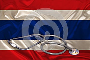 Doctorâ€™s tool, medical stethoscope, lies on the silk national flag of the state of Thailand, concept of tourism, insurance,