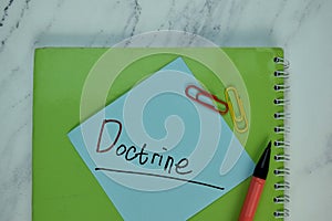 Doctrine write on sticky note isolated on Wooden Table