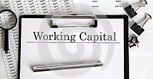 Document with text WORKING CAPITAL with chart, pen and magnifier