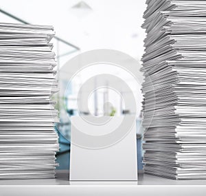 Documentation. A stack of white papers lie on a desk in an office room.