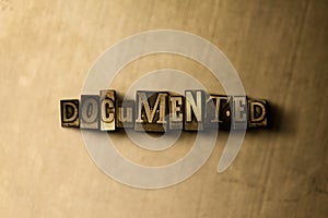 DOCUMENTED - close-up of grungy vintage typeset word on metal backdrop