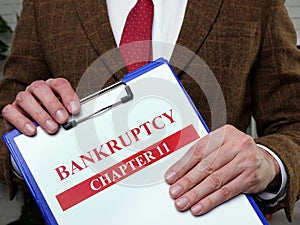 Documents about bankruptcy chapter 11. Man holds papers.