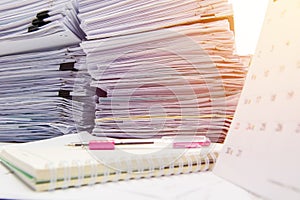 Documents on desk stack up high waiting to be managed