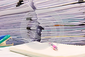 documents on desk stack up high waiting to be managed..