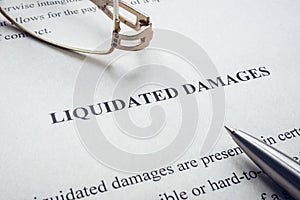 Documents about Liquidated damages with pen and glasses.