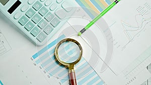 Documents with magnifying glass and calculator. Printed stock graphs and charts. Analyzing financial data report and