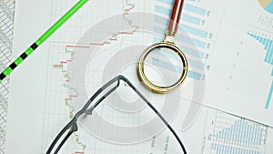 Documents with magnifying glass. Printed stock graphs and charts. Analyzing financial data report and business concept