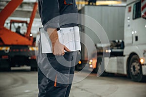 Documents in notepad. Male worker is in the modern warehouse or manufacturing company