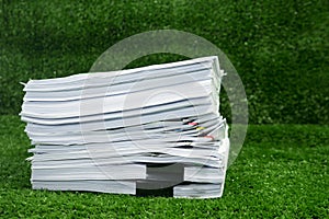 Documents pile on grass in concept save Earth