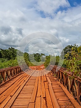 Dodgy wooden bridge with timber planks and old iron rails crossing river in Gabon, Central Africa