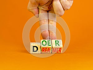 Doer or dreamer symbol. Concept words Doer or dreamer on wooden cubes. Businessman hand. Beautiful orange table orange background