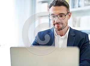 He does all his work online. a businessman working on his laptop in his office.