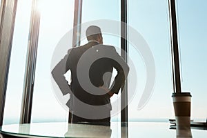 He does business on a whole new level. Rearview shot of a young businessman looking out the window in an office.