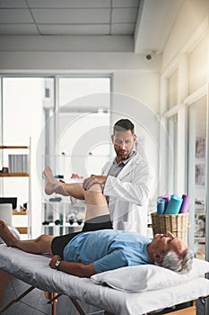 Does it hurt when I press here. a young male physiotherapist assisting a senior patient in recovery.