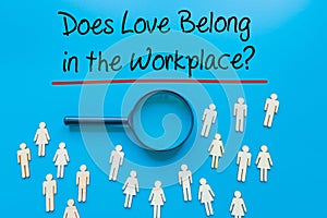 Does Love Belong in the Workplace? Sign on white paper. Man Hand Holding Paper with text. Isolated on Workers concept, Magnifying