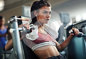 She doesnt wimp out on her workouts. a young woman working out with a chest press at a gym.