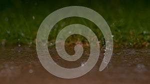 DOF: Beautiful shot of glassy raindrops falling into murky pond during rainstorm