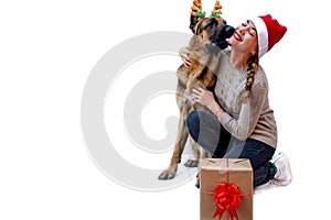 Dog with deer antlers kisses girl in Santa hat. Woman and pet celebrates new year and Christmas. Greeting card with a German