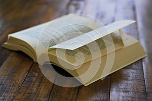 Dog eared paperback book on worn wooden surface