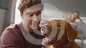 Dog enjoy owner caress in apartment close up. Woman looking on man stroking pet photo