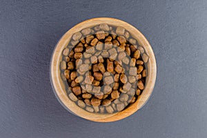 Dog food in a bowl on black background, flat lay