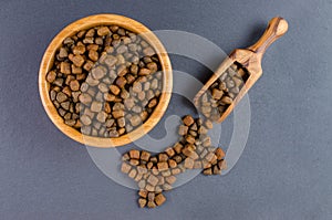 Dog food in a bowl and snack like bone on black background, top view