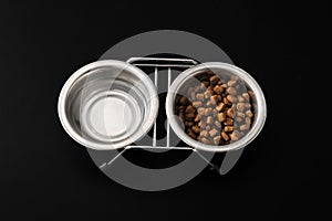 Dog food in a metal bowl on black background.