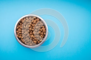 Dog food in a metal bowl. Blue background