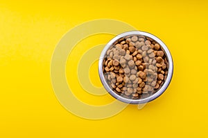 Dog food in a metal bowl. Yellow background