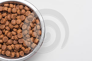 Dog food in a silver bowl. Half of the bowl on the left. White background. Copy, text sapce