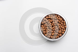 Dog food in a silver bowl. On the right. White background. Copy, text sapce