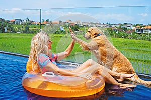Dog give high five to happy girl swimming in pool