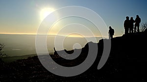 Dog and hikers silhouette on top of the mountain at sunset