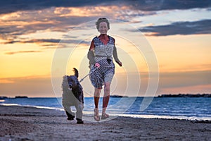 Dog with his mistress running on the beach by the sea