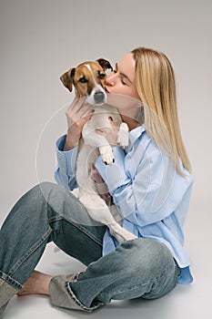 Dog kiss. Beautiful blonde dog owner kissing her small white pet