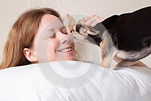 Dog kisses happy woman in bed, sleep with pet, love and friendship with animals