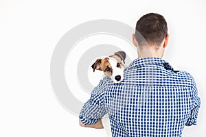 The dog lies on the shoulder of its owner. Jack Russell Terrier in his owner`s hands on white background. The concept of people an