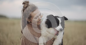 Dog lover stylish girl wearing sunglasses hugging her doggy during they walk. Portrait of smiling young woman kissing